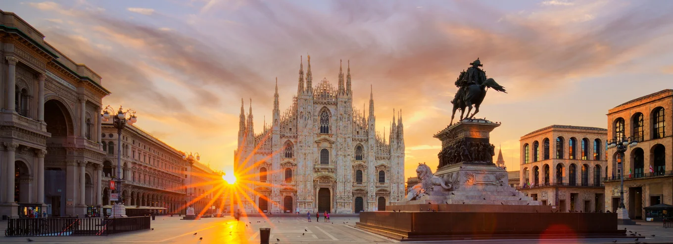 Sunrise over Milan Cathedral, statue in plaza.
